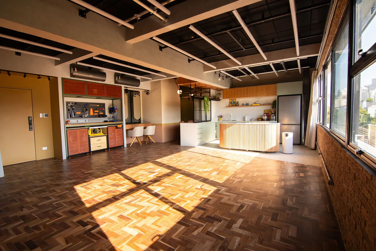 Loft do Espaço Híbrido: área de criação e produção com a cozinha ao fundo