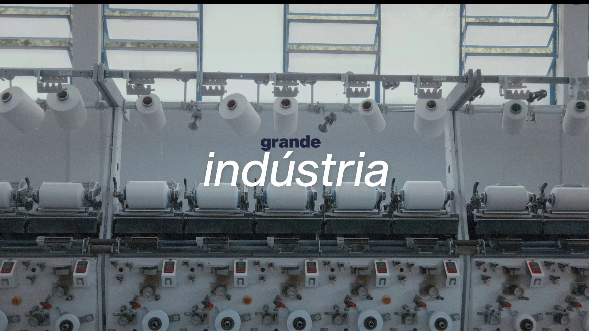 Máquinas de fiação industrial enfileiradas sob as palavras grande indústria.