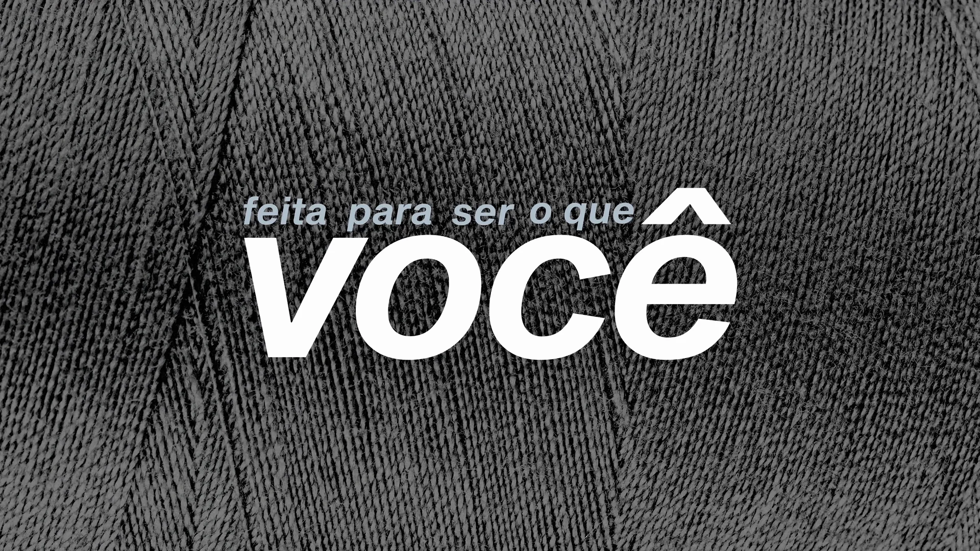 Frase feita para ser o que você, em letras brancas sobre trama de fio escura.