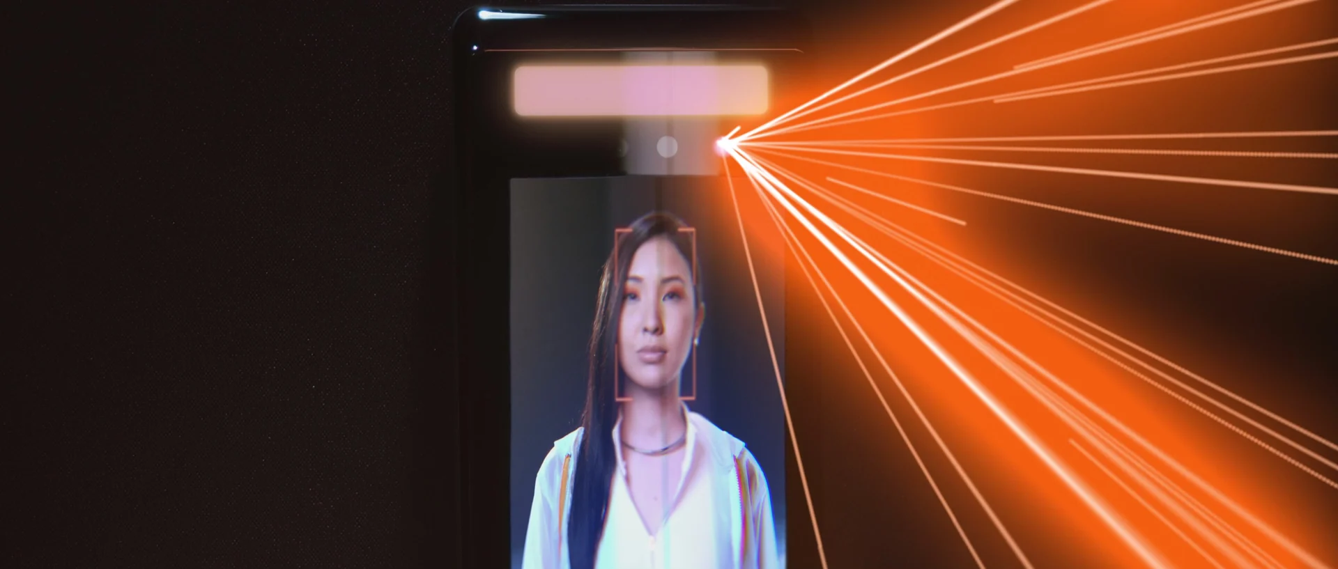 Na tela do leitor facial aparece o rosto da atriz, atravessado por raios de luz laranja que se abrem em leque.