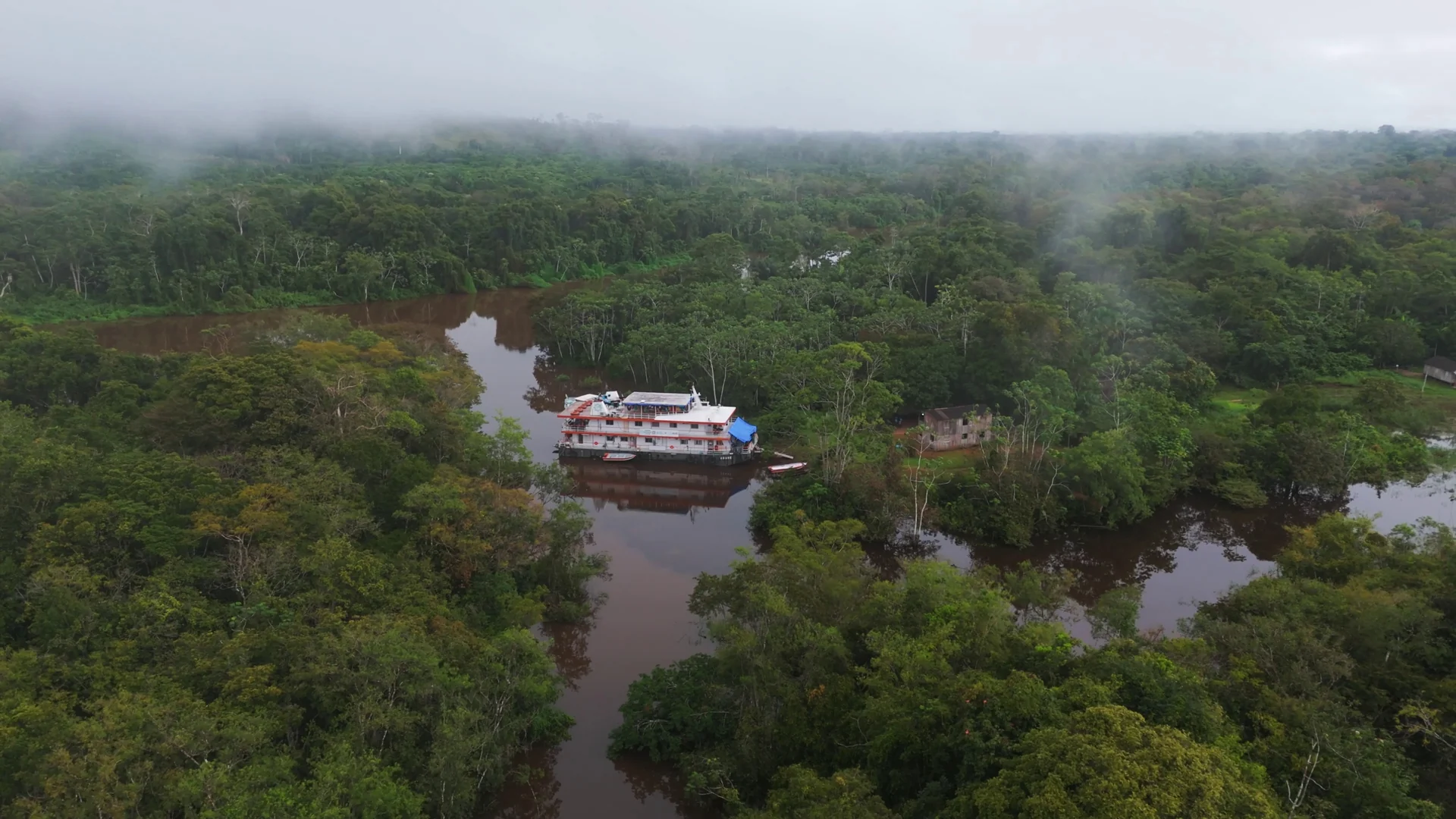 Vista aérea do navio-hospital Abaré atracado entre a floresta alagada, sob névoa baixa.