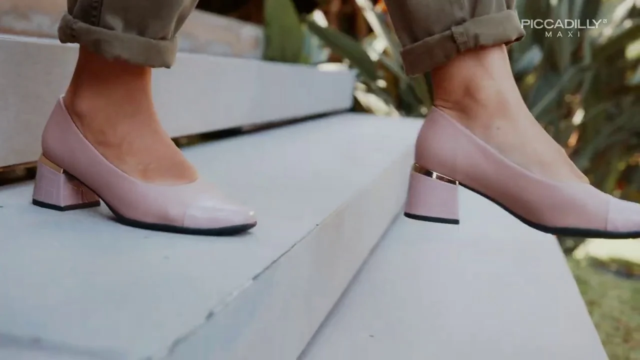 Pés com sapatos rosados de salto bloco sobem degraus claros.