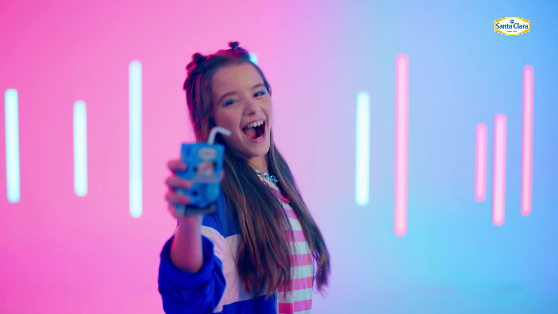 Menina sorri e canta segurando a caixinha azul de Chocolate Que Gela!.
