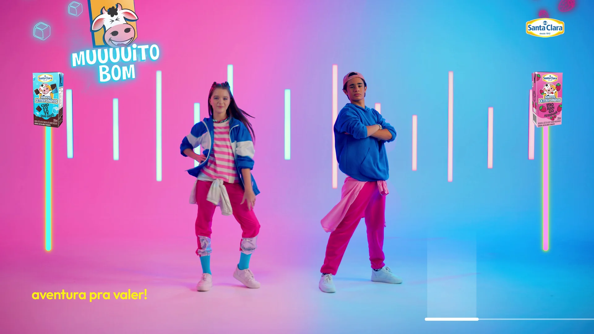 Os dois atores em pose final, com a vaquinha da marca, o selo Muuuuito Bom e caixinhas flutuando nas laterais.