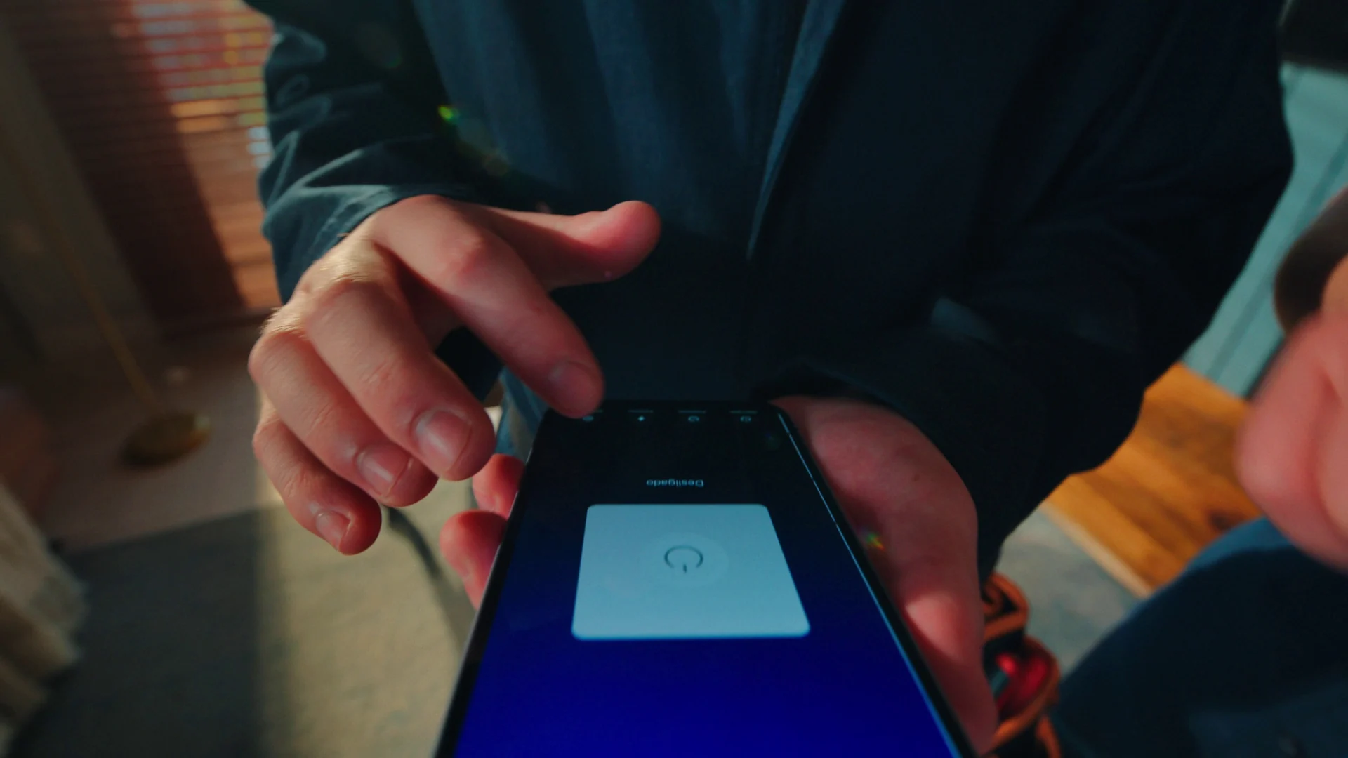 Mãos tocam a tela de um smartphone com o app T Smart aberto para controlar a iluminação.