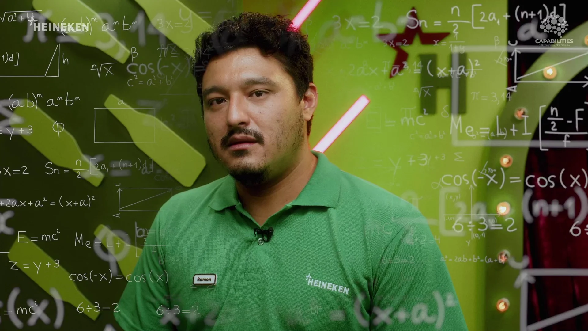 Participante de camisa polo verde olha pensativo enquanto fórmulas matemáticas animadas flutuam ao seu redor no estúdio.